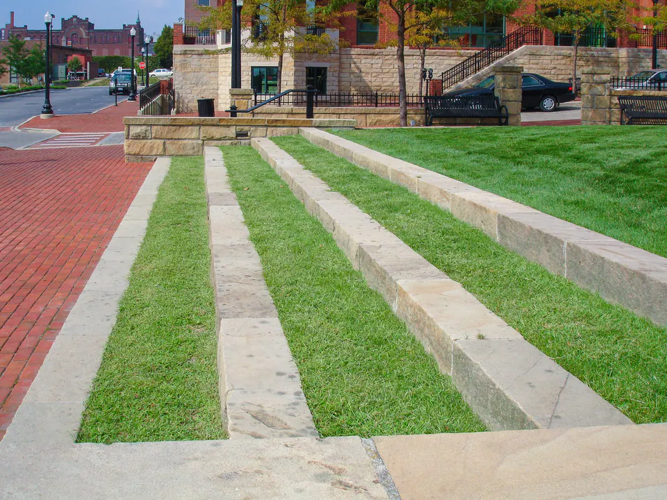 Stone stair bands with narrow lawn strips and brick paving at a commercial courtyard.